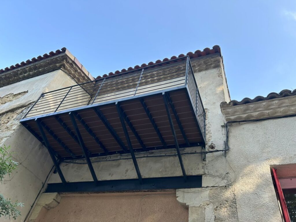 Ossature d’un balcon en acier vue de dessous, platelage bois et garde-corps
