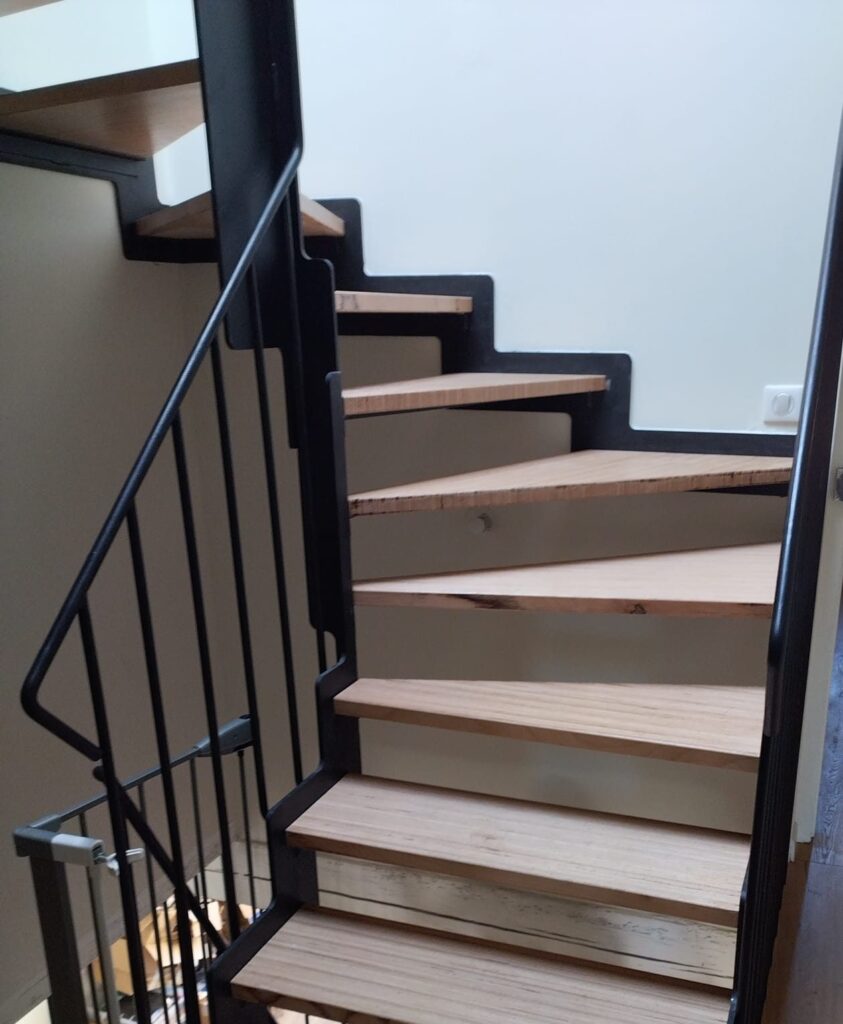 Escalier quart tournant, limons crémaillère en acier noir, marches en bois et rampe à barreaux